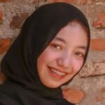 woman in black hijab and black long sleeve shirt sitting on brown chair